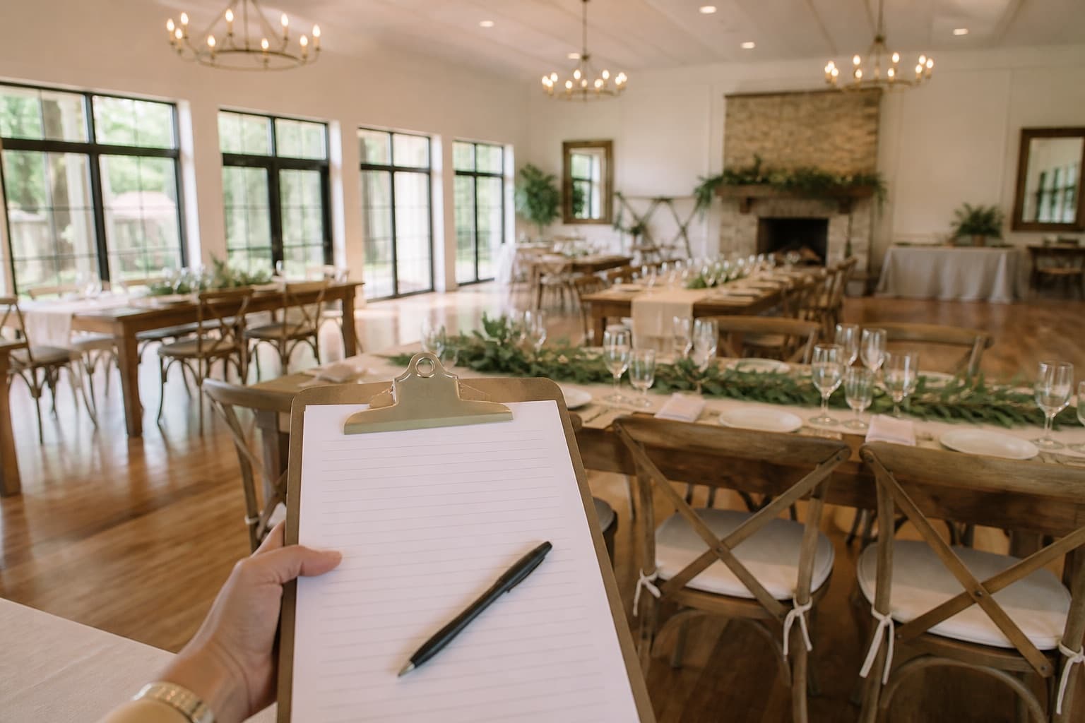 A clipboard held in the foreground of an empty wedding reception venue.